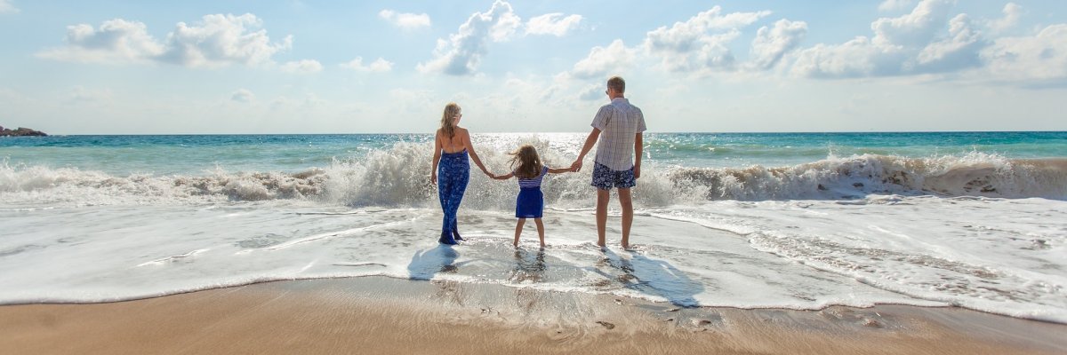 Eltern stehen mit Kind am Strand